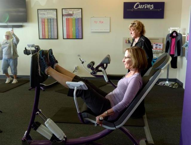 CENTENNIAL, CO - APRIL 15: Fit through menopause at Curves, 7424 S. University Blvd. in Centennial on Wednesday, April 15, 2015 coach Joyce Myers works the leg press machine as she helps customers on the floor of the gym use the hydraulic equipment to maintain strength. (Photo by Cyrus McCrimmon/The Denver Post )